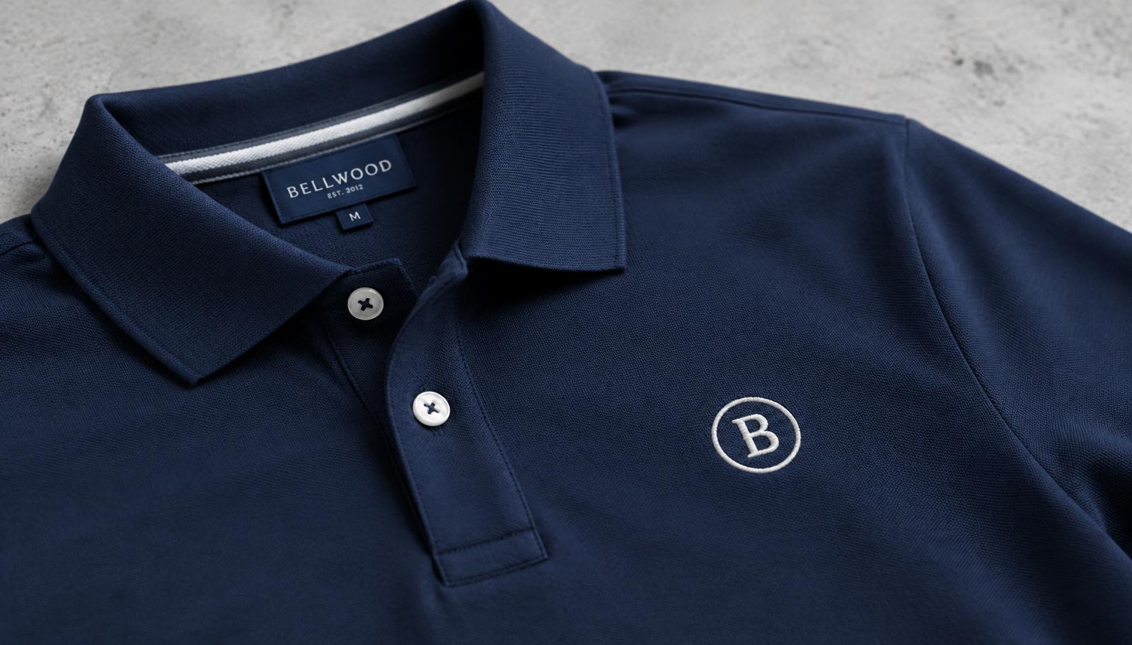 Close-up of a navy polo shirt with an embroidered circular B logo on the chest